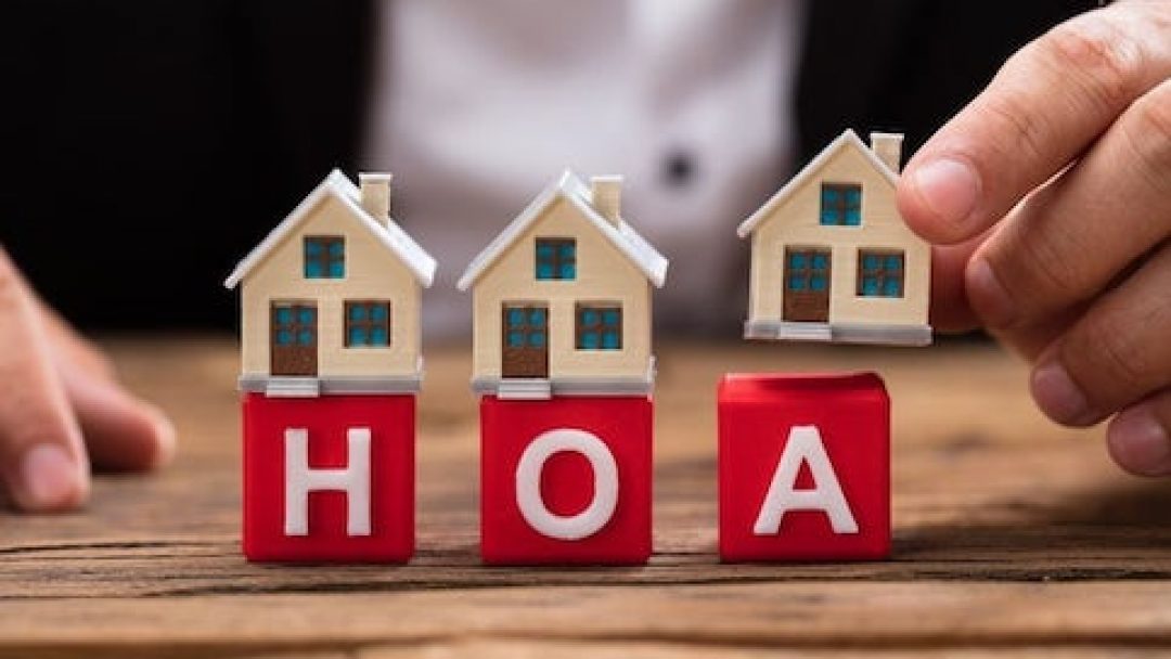 Model houses on blocks spelling HOA, representing condo association dues and homeowners' association costs